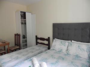 um quarto com uma cama com uma cabeceira cinzenta e lençóis brancos em Aconchego Valparaíso em Petrópolis