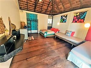 ein Wohnzimmer mit 2 Betten und Holzböden in der Unterkunft MOOREA - Local Spirit 6 in Hauru