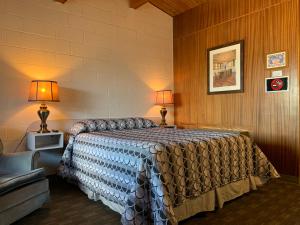 1 dormitorio con 1 cama, 2 lámparas y sofá en Ace Crown Motel, en Medicine Hat