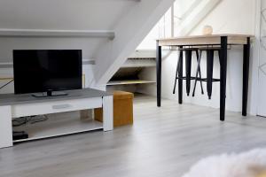 a living room with a tv and a table with a television at La porte bleue in Baie-Mahault