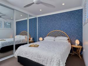 a bedroom with two beds and a blue wall at Casuarinas 5 superb waterfront unit in Soldiers Point
