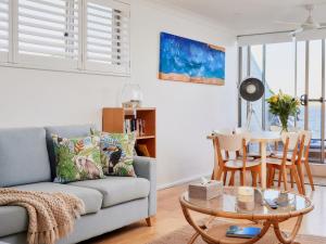 a living room with a couch and a table at Casuarinas 5 superb waterfront unit in Soldiers Point