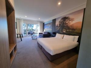 a bedroom with a large bed and a living room at Mercure Gerringong Resort in Gerringong