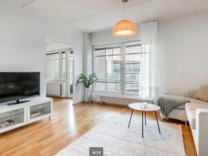 a living room with a couch and a tv at Scandinavian design heart City Center Runeberginkatu in Helsinki