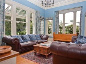 a living room with leather couches and a piano at Lilac Rose Boutique Bed and Breakfast in Christchurch