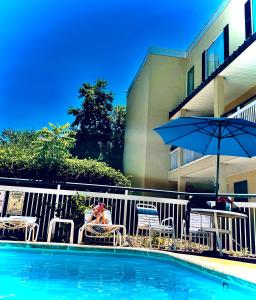 a pool with chairs and an umbrella next to a building at Days Inn by Wyndham Chattanooga/Hamilton Place in Chattanooga