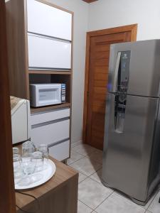 a kitchen with a stainless steel refrigerator and a microwave at Casa Schmidt Centro Pedra Azul in Pedra Azul