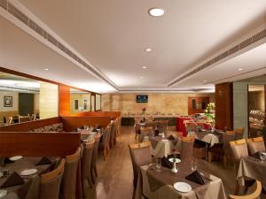 Sivaraj Inn Salem في سالم: مطعم فيه طاولات وكراسي في الغرفة