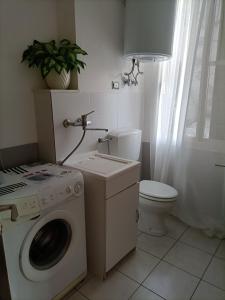 a bathroom with a washing machine and a toilet at Apparamento Raysol in Agnone Bagni