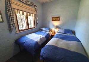 two twin beds in a room with a window at Griffiths Cottage in Burra