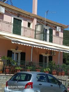 un coche aparcado frente a una casa rosa en CHRYSPY Toulatos Studios en Pouláta