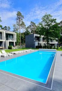 a large swimming pool with chairs and a building at BOHO MARE Apartament Pobierowo in Pobierowo