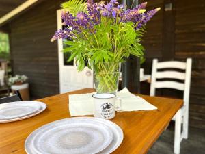 un vaso di fiori viola seduto su un tavolo di legno di apartamenty lajkonik a Dąbrówno