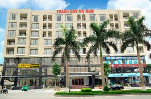 Thanh Dat Hotel I في Ninh Lão: مبنى ابيض كبير امامه نخيل