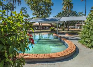 a swimming pool with a canopy in a park with trees at Contour Hotel Katherine in Katherine
