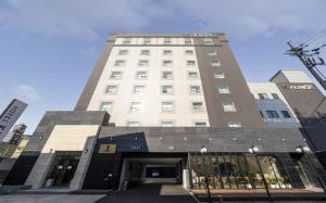 a tall white building with a door in front of it at KNox Hotel in Cheonan