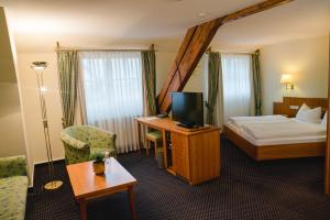 a hotel room with a bed and a desk with a television at Landhotel Hirschen in Oberwolfach