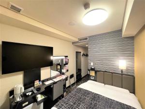 a bedroom with a bed and a flat screen tv at APA Hotel Hachioji Eki Nishi in Hachioji