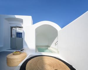 a white room with a swimming pool and a round rug at Betty's Home Santorini in Karterados