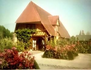 een huis met een groot dak en wat bloemen bij Le chasse marée in Offranville