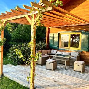 a wooden pergola with a couch and tables on a deck at Holz Chalet Nähe Salzburg in Feldbach