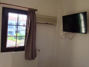 a television hanging on a wall next to a window at Despina Lymperi Hotel Apartments in Myrina