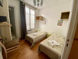 a room with two beds and a chair and a window at Boutique Hotel Couleurs Suds in Cannes