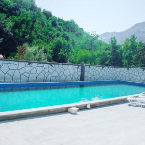 a swimming pool with blue water and a stone wall at Spitak Tun in Ijevan