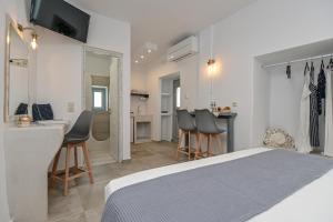 a bedroom with a bed and chairs and a kitchen at Venetian Suites II in Naxos Chora