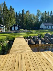 a wooden bridge over a river with a house in the background at Villa Muikkupolku in Kokkola