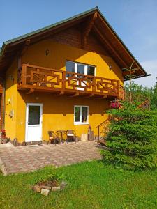 a yellow house with a balcony and a patio at Приватна Садиба Потічок in Slavske