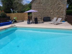 a swimming pool with two chairs and an umbrella at LA ROCQUE in Bonnemain