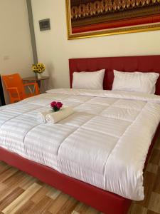 a bed with a red head board with a flower on it at PP Nongkhai Resort in Nong Khai +1 photo