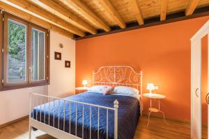 een slaapkamer met een bed met een oranje muur bij Le Pleiadi Merope in Gardone Riviera