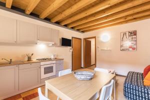 kuchnia i jadalnia z drewnianym stołem i krzesłami w obiekcie Le Pleiadi Merope w mieście Gardone Riviera