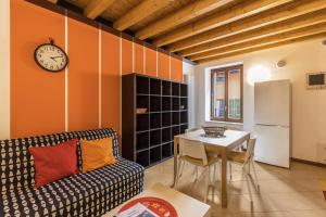 een woonkamer met een bank, een tafel en een klok bij Le Pleiadi Merope in Gardone Riviera