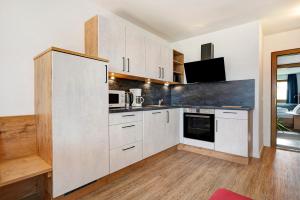 cocina con armarios blancos y encimera en Residence Condor Apt Eidechsspitz, en Maranza