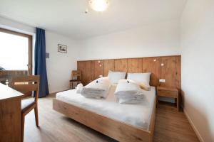 1 dormitorio con 1 cama grande con sábanas y almohadas blancas en Residence Condor Apt Eidechsspitz, en Maranza