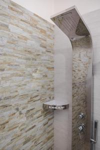 a shower in a bathroom with a stone wall at Villetta Giorgia Torre Suda in Torre Suda