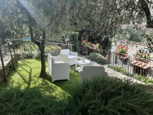 フィエーゾレにあるCasa Vacanze Adaの白い椅子2脚と木のある庭園