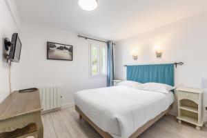 a white bedroom with a bed and a window at Hotel Le Clos Fleuri in Le Palais