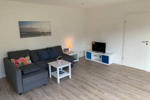 uma sala de estar com um sofá e uma televisão em Near „Hamburg summer lounge“ cozy sunny green em Quickborn