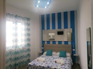 Schlafzimmer mit einem Bett mit blauen und weißen Streifen in der Unterkunft B&B 36 Passi dal mare 2.0 in Trapani