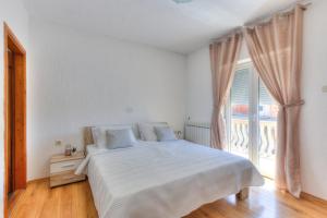 a white bedroom with a large bed and a window at Apartments Kristijan in Senj