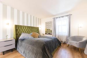 um quarto com uma cama grande e uma cadeira em De Merin Boutique Hotel Straden em Straden