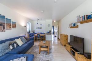 a living room with a blue couch and a tv at Villa Anna ll App 73 in Sankt Peter-Ording