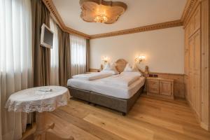 a bedroom with a bed with a table and a chandelier at Appartments Peter in Colfosco