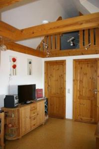 a living room with two wooden doors and a television at Boddenkieker in Born