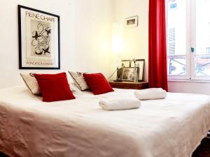 a bedroom with a large white bed with red pillows at Montmartre Apartments Monet in Paris