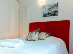 a bedroom with a white bed with a red headboard at Montmartre Apartments Dalida in Paris